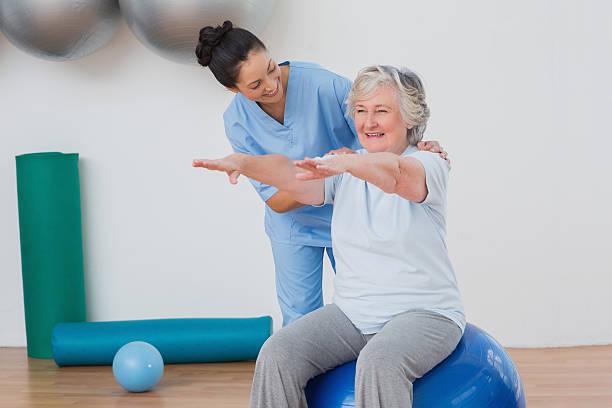 Physiotherapist helping an older woman with a seated rehabilitation exercise